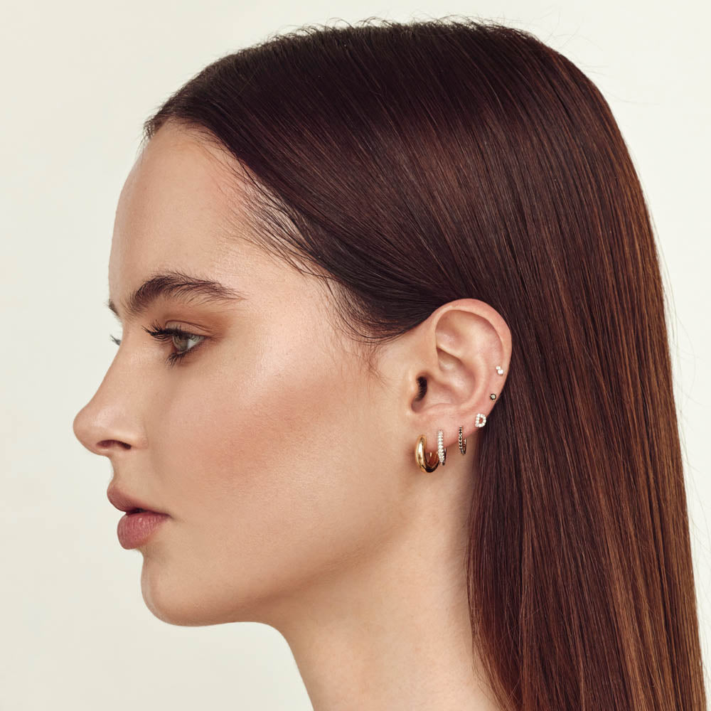 woman showing multiple lobe, cartilage and helix piercings in ear